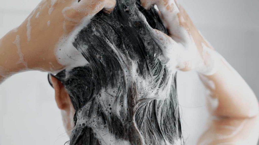 lavando el cabello con champú para quitar la pintura en aerosol